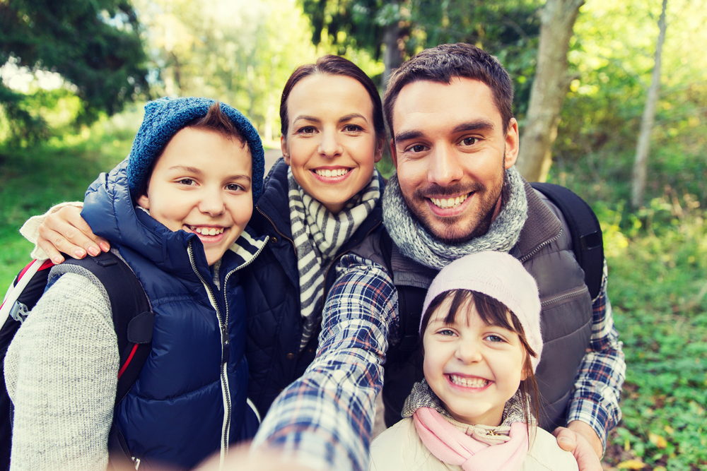 happy family with backpacks taking selfie and hiking and seeing clearly