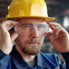 factory worker with beard adjusting protective goggles in industry who no longer has to hassle with eyeglasses stuck under his goggles